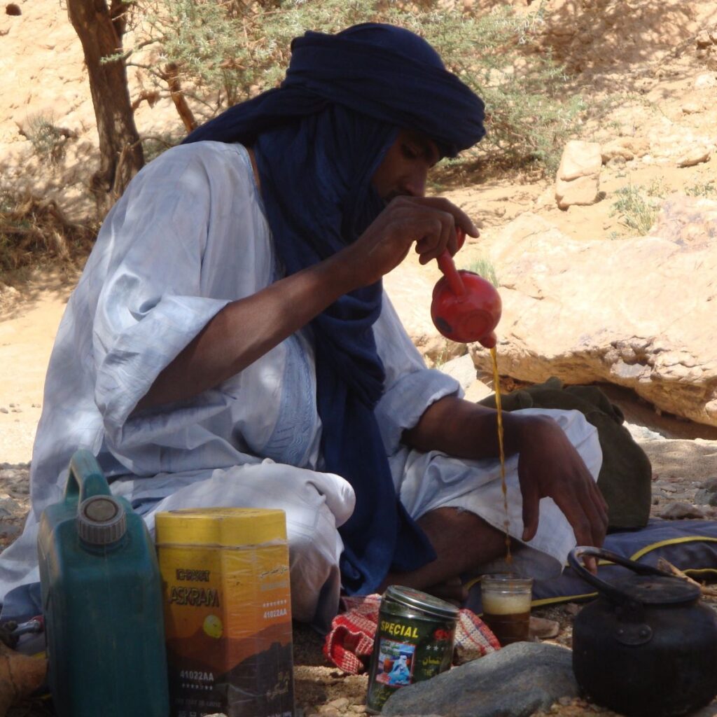 Malek, un Touareg, prépare le thé traditionnel dans le Sahara du sud algérien et le verse d’une grande hauteur