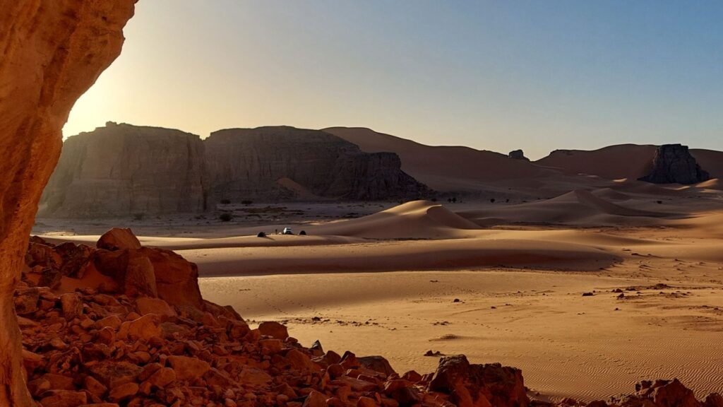 Camp in der Tadrart Rouge bei Sonnenaufgang, umgeben von Felsformationen und Sanddünen