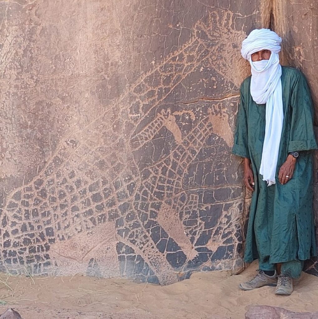 Abdallah devant les anciennes gravures de girafes dans la Tadrart Rouge, en Algérie